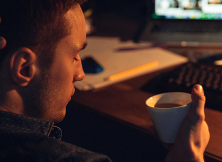 Man in dark on laptop looking stressed